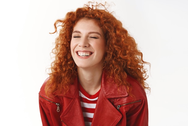 Closeup carefree redhead curlyhaired ginger girl express happiness and positivity close eyes laughing having fun lucky day smiling broadly wear red jacket enjoy beautiful day enthusiastic mood