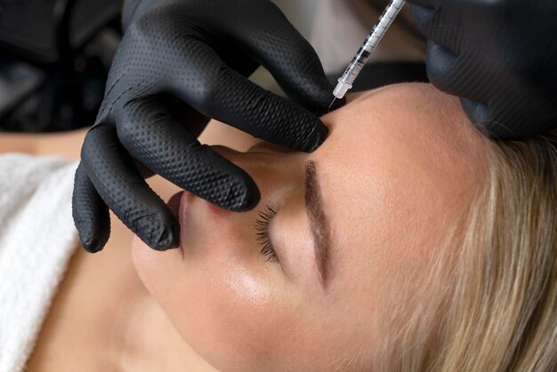 Photo closeup of caucasian woman gets botox cosmetic injection in forehead beauty physician inserts