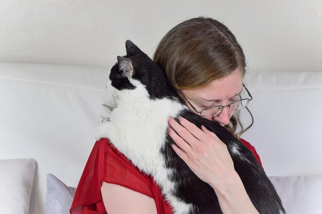 Photo closeup of caucasian woman holding a black and white cat who decided to interrupt a photo shoot by crawling onto her shoulder