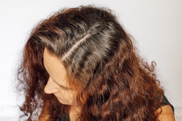 Photo closeup of caucasian young woman graying hair roots on white background regrown roots which are in need of recoloring anti age self care copy space