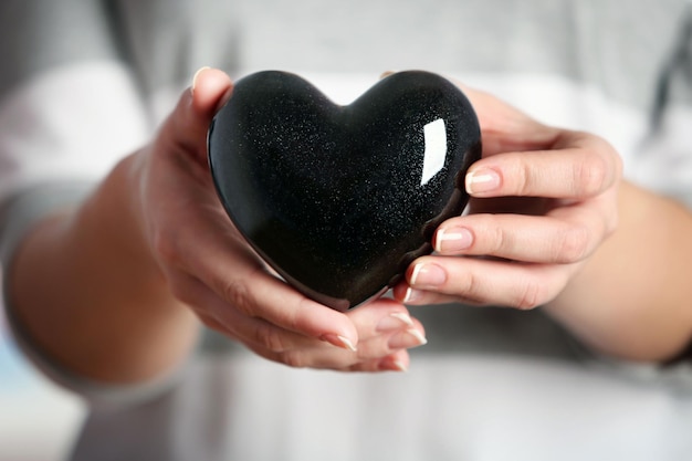 Closeup of ceramic black heart in female hands