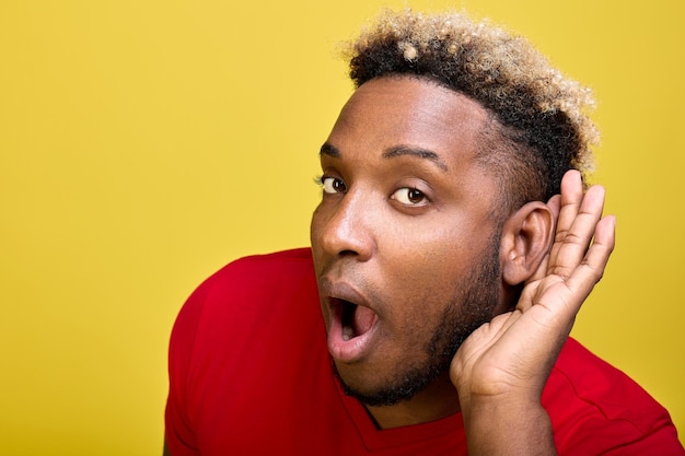 Closeup of cheerful black guy listening with his ear secret information