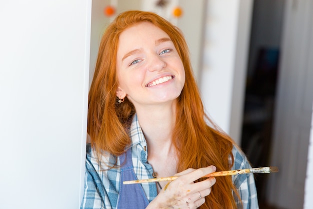 Closeup of cheerful happy attractive young woman painter with brush