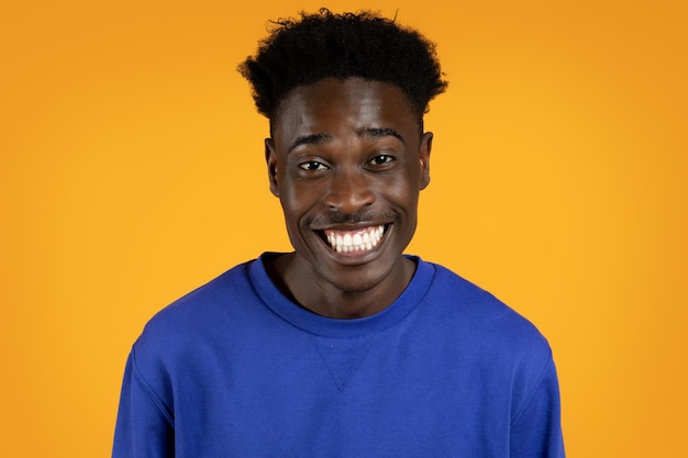 Closeup of cheerful young black guy smiling on yellow