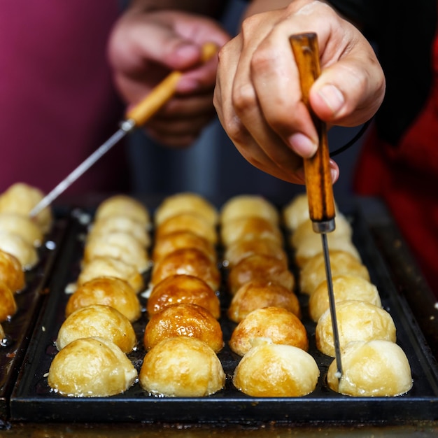 Closeup Chef handen Koken Takoyaki op hete pan in straatvoedsel