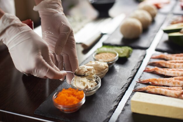 Primo piano delle mani di chef che preparano cibo giapponese. cuoco unico giapponese che fa i rotoli di sushi al ristorante.