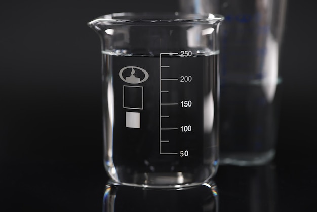 Photo closeup of chemical beaker with water on black background