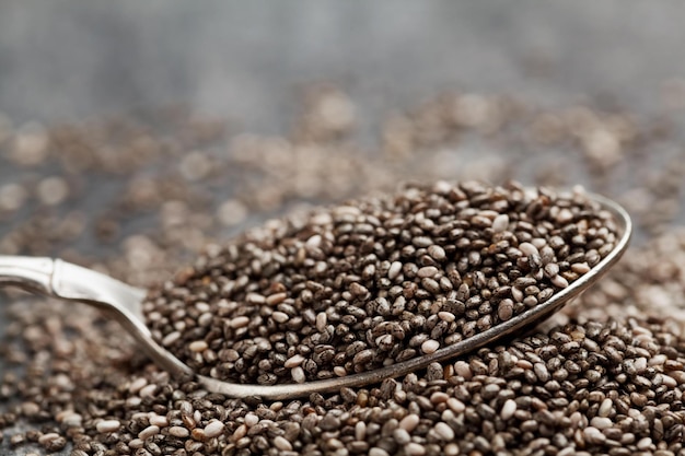 Closeup chia seeds in silver spoon on black table superfood copy space for text