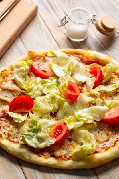 Closeup on chicken caesar pizza with tomatoes and lettuce