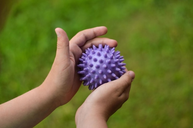 Крупный план детских рук, держащих фиолетовый колючий антистрессовый мяч