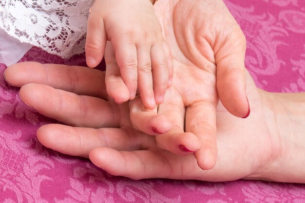 家族と彼らの赤ちゃんへの愛のママとパパの概念の子供の手のクローズアップ