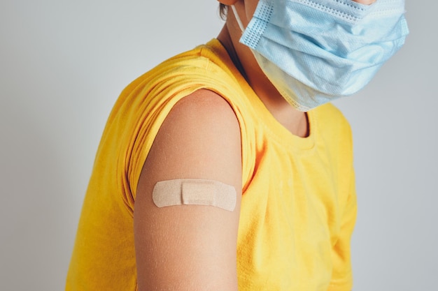 Крупный план детского плеча с бинтом после вакцинации или инъекции антибиотиков
