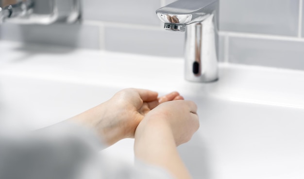 Closeup the child washes his hands in the bathroom