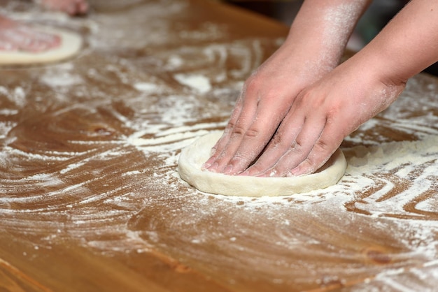 Крупный план детских рук, готовящих тесто для пиццы