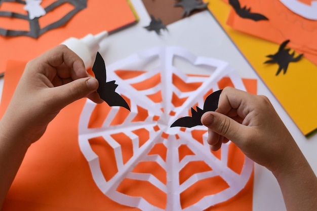 Closeup of children's hands that create paper crafts for Halloween Homemade decorations for the holiday