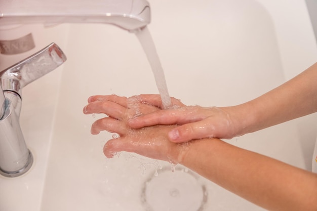 Closeup of childrens hands The child washes under the tap of the palm on a white background