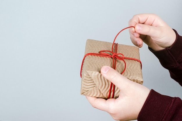 Closeup of childrens hands unpacking a Christmas present handmade from Kraft paper