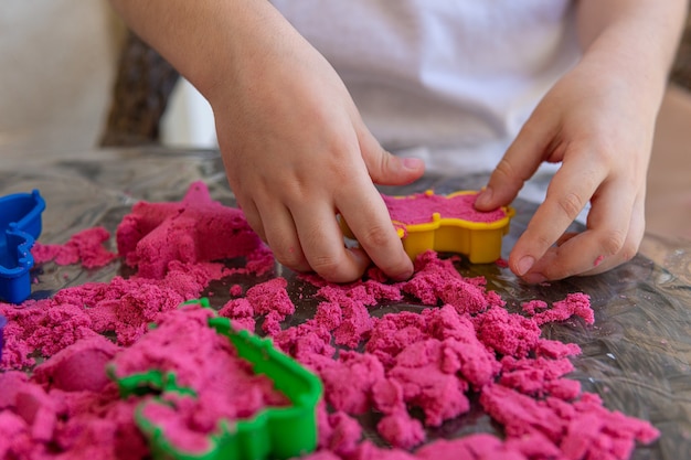 Photo closeup of childs hands playing in kinetic sand