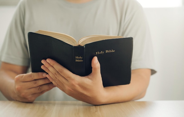 Foto prossimo piano delle mani di un uomo cristiano mentre legge la bibbia istruzione biblica spiritualità e religione