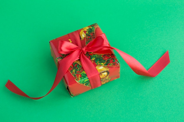 Closeup on Christmas gift  with red ribbon on the green background