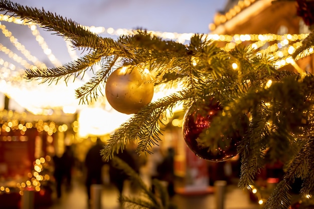 Primo piano di un ramo di un albero di natale con giocattoli di palline decorative e una brillante ghirlanda soft focus