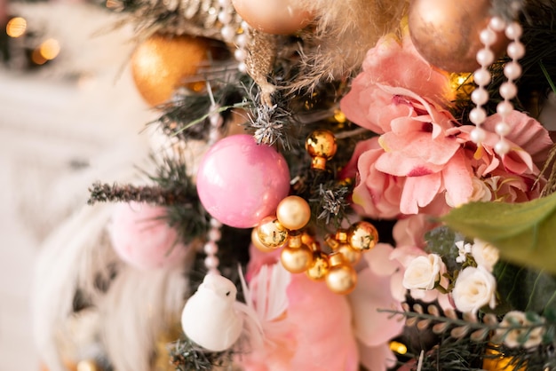 Primo piano di un albero di natale decorato con fiori rosa e palline dorate