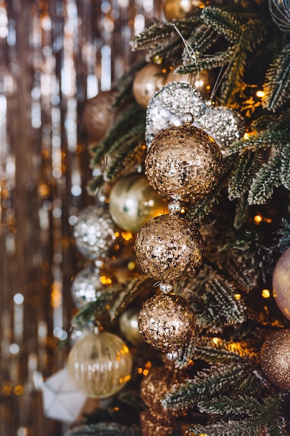 Closeup of Christmas tree with golden and silver toy balls and garland The foreground is in focus