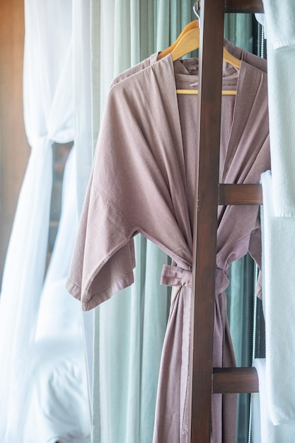 Closeup clean bathrobe and towel hanging in wooden wardrobe at luxury hotel. Relax and travel concept