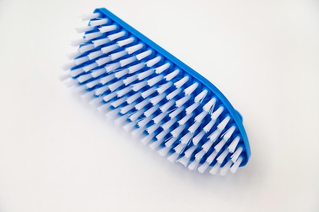 Closeup cleaning brush on a white background A brush with a white pile and a blue handle Convenient equipment for cleaning the house
