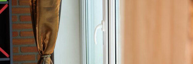 Closeup of closed handle of white pvc window in flat modern large plastic window