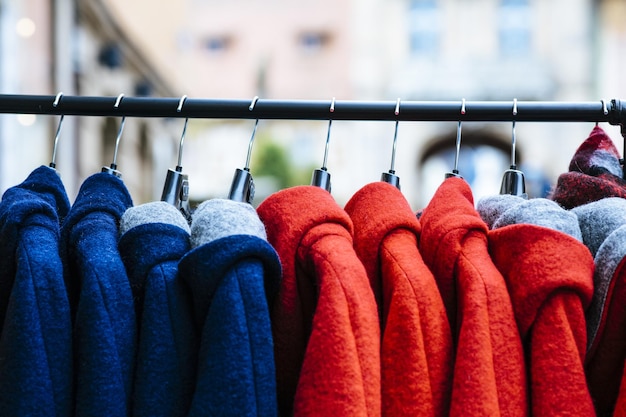 야외에서 파란색과 빨간색 코트가 있는 옷걸이를 닫습니다.