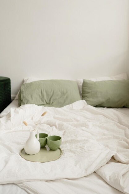 Closeup of a coffee cup on the bed with green pillows