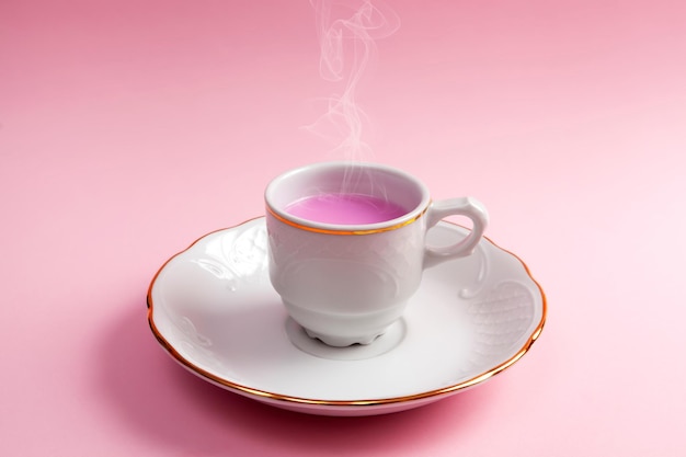 Closeup of coffee cup and plate with rose coffee or tea Pink background Minimalism