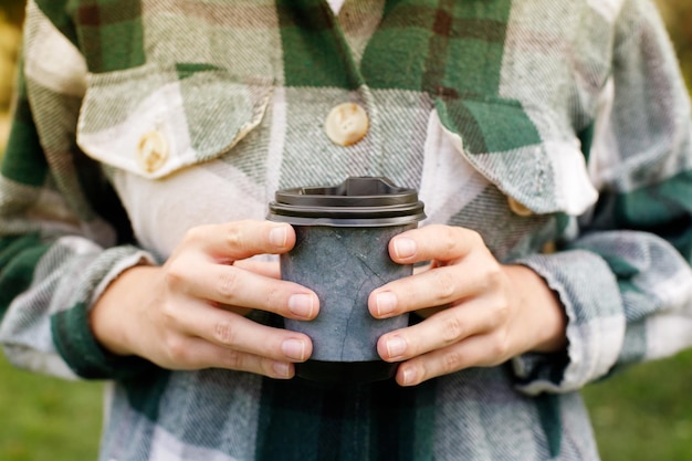 Closeup of coffee to go with a woman in her hands on a walk