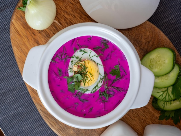 Primo piano di zuppa fredda chlodnik su una tavola di legno zuppa di cucina polacca bielorussa e russa a base di barbabietola e kefir decorata con mezzo uovo cibo sano vista dall'alto piatto