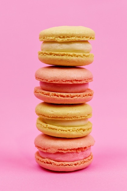 Closeup of colored yellow macaroons or macarons in pastel tones on a pink background