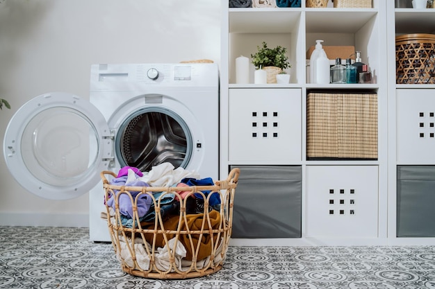 Closeup of colorful clothes in basket open washing machine standing in background