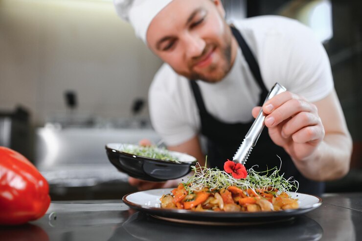 Photo closeup of a concentrated male chef garnishing food in the kitchen