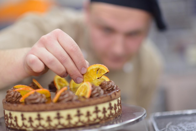부엌에서 디저트 케이크 음식을 장식하는 집중된 남성 패스트리 셰프의 클로즈업