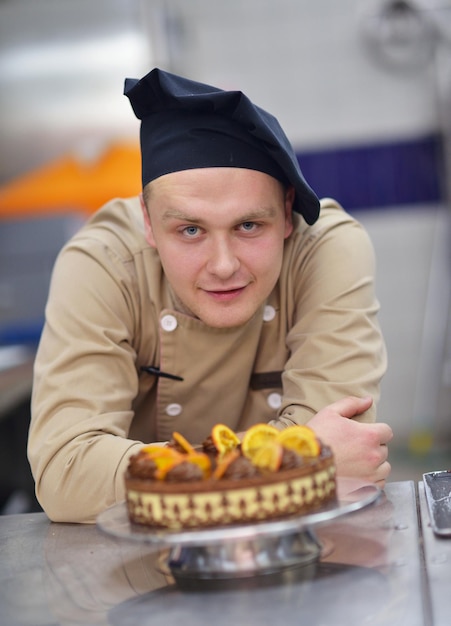 Closeup of a concentrated male pastry chef decorating dessert cake food in the kitchen