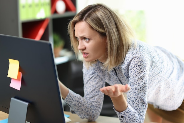 Closeup of confused and upset woman looking at computer screen financial problem unexpected