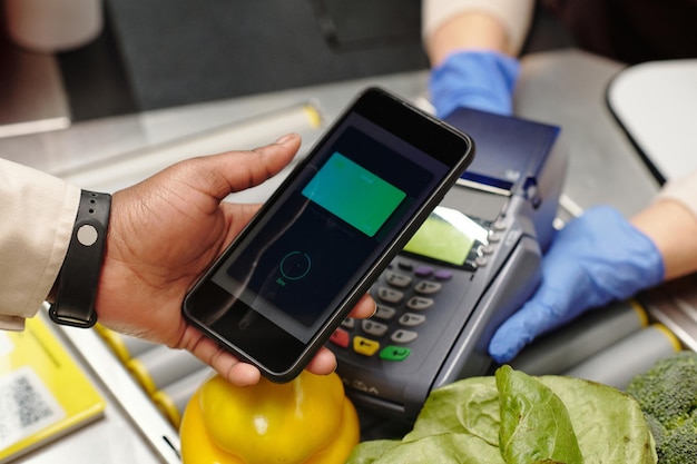 Closeup of consumer hand holding smartphone over card reader