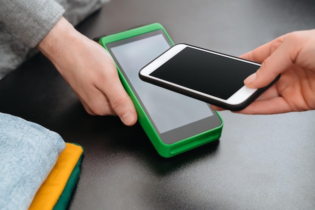 Closeup of contactless payment with smartphone in clothes shop