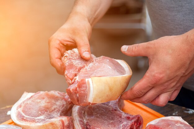 Крупный план повара намазывает соусом и солит большие куски антрекота из свежей свинины для гриля