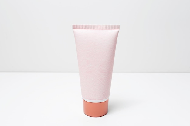 Closeup of cosmetic tube bottle of pastel pink color on whitegrey background