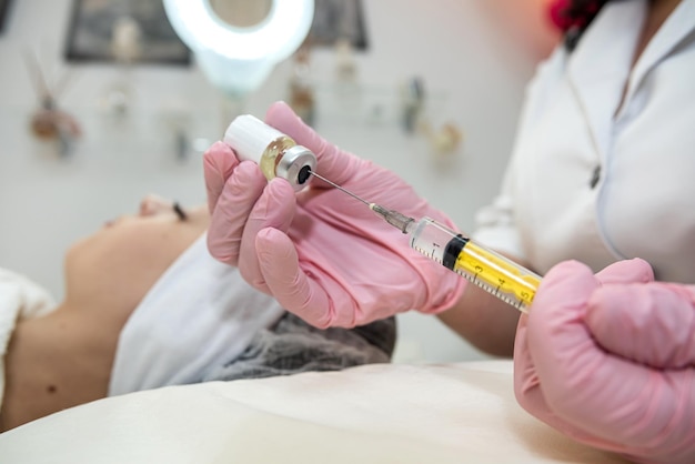 closeup of cosmetologist hand doing treatment procedure with injecting botox in woman client face