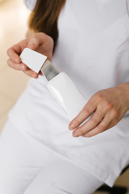 Closeup of a cosmetologist woman opening a device for ultrasonic facial cleansing