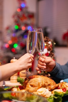 Primo piano di una coppia che si scontra con un bicchiere di vino durante la cena di natale
