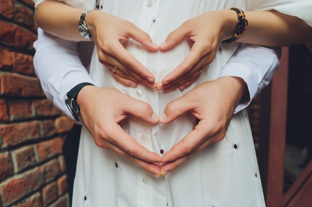 Closeup of couple making heart shape with hands.