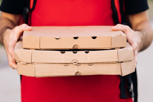 Closeup of the couriers hands and pizza portrait of delivery man holding cardboard pizza box